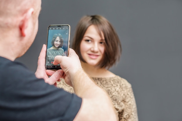 Young man is taking photo by smartphone for young woman