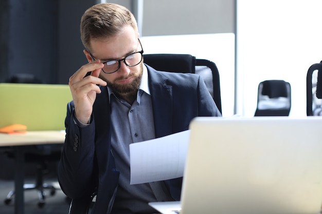 Young man is working with papers while sitting in the office.