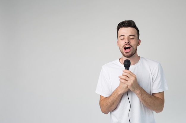 Young man isolated over background holds microphone in hand