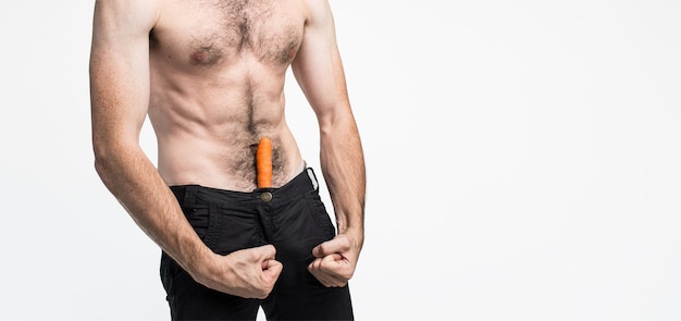 Young man isolated over background. Picture of guy has carrot in his pants and show he is sexual and powerful. Well-built strong body. Pale skin