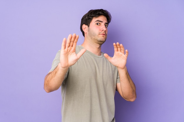 Young man isolated on purple being shocked due to an imminent danger