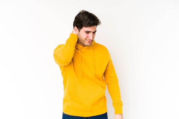 Young man isolated on white having a neck pain due to stress, massaging and touching it with hand.