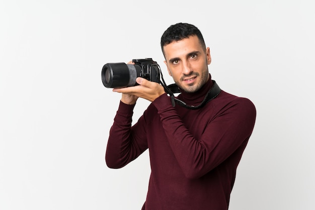 Young man over isolated white  with a professional camera