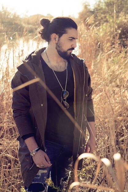 Young man in jacket on the shore of a lake