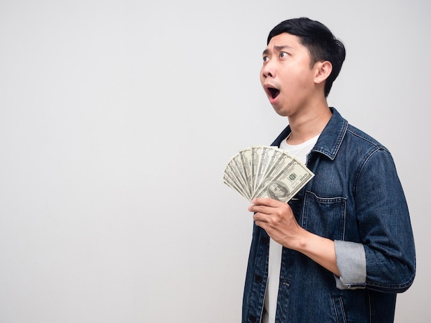 Young man jeans shirt hold money feels shocked looking at copy space