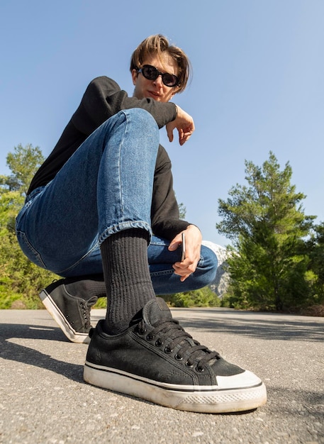 Photo young man in jeans and sneakers sits on the road in the woods