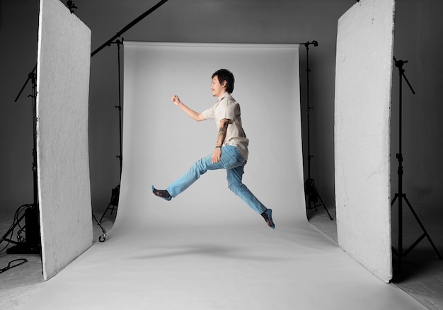 Photo young man jumping against white backdrop