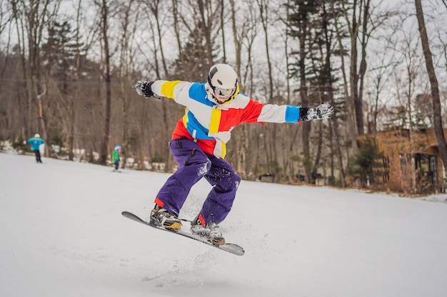 Young man jumping with a snowboard in the mountains