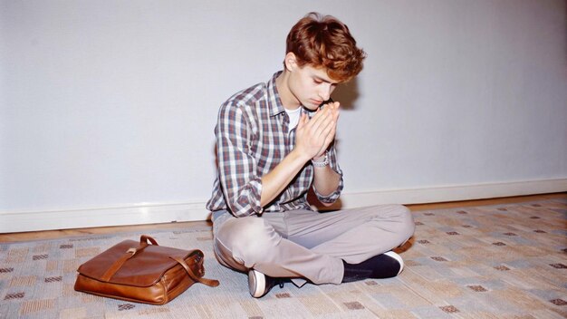 a young man kneeling on the floor with his hands clasped young praying