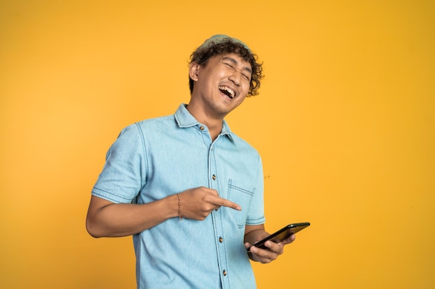 Young man laugh hard when looking at a mobile phone