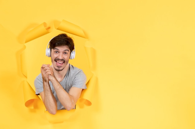 young man listening to music in headphones on yellow background audio ultrasound sound