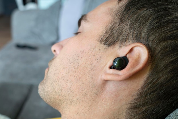 Young man listening to music lying on couch Concepts of day rest and listening to music Sleep with music