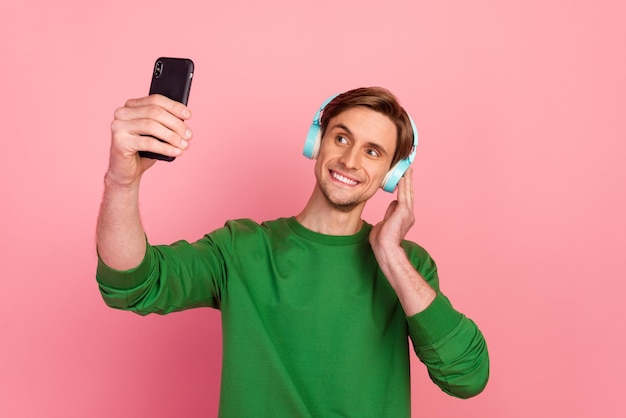 Young man listening music wearing headphones bright sweatshirt enjoying favorite tracks isolated pastel background