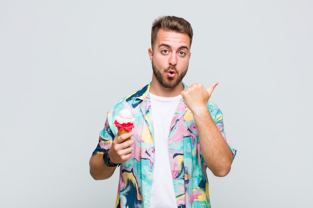 Young man looking astonished in disbelief, pointing at object on the side and saying wow, unbelievable