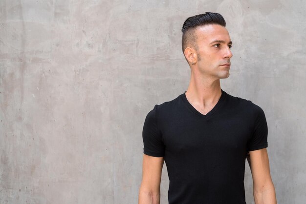 Photo young man looking away while standing against wall