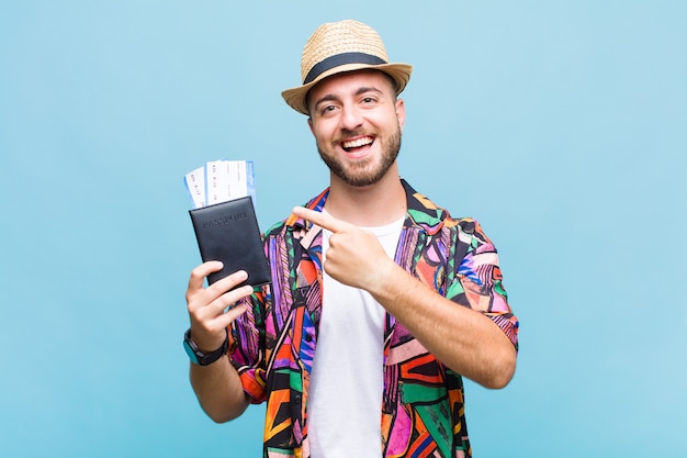 Young man looking excited and surprised pointing to the side and upwards to copy space