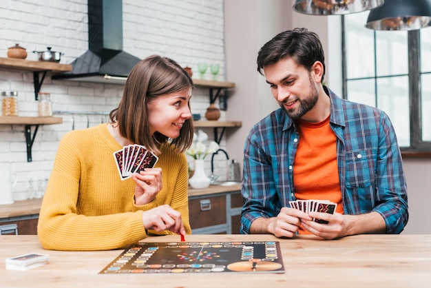 Young man looking at her wife playing the board game on wooden desk