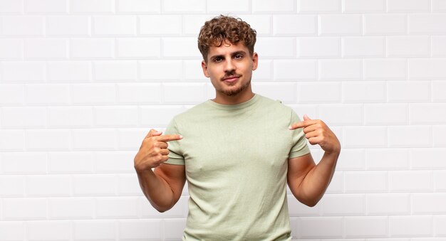 Photo young man looking proud, positive and casual pointing to chest with both hands