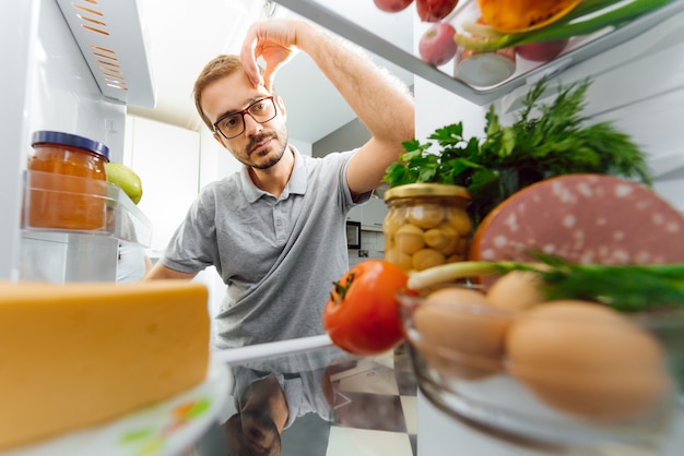 Young man looking in the refrigerator