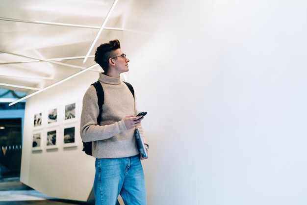 Young man looking at white blank wall