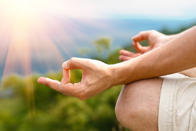 Photo young man in lotus pose. man practicing yoga outdoors