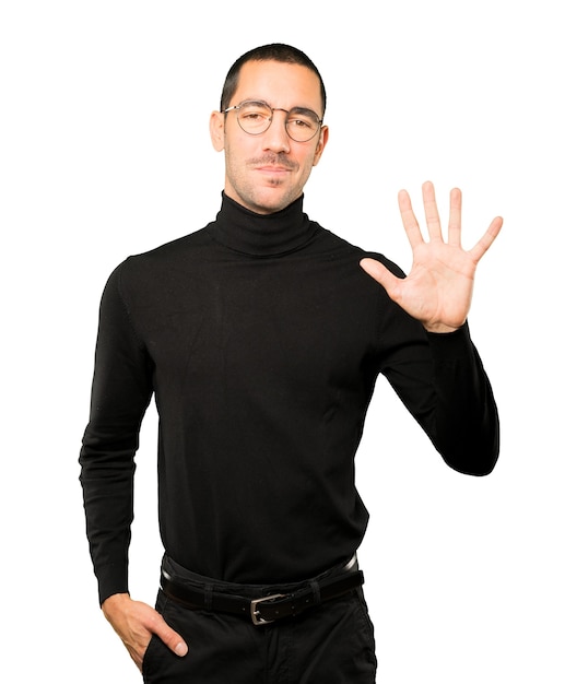 Young man making a number five gesture