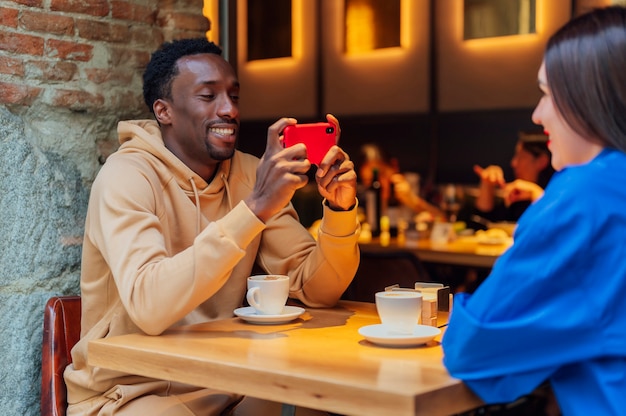 Young man making selfie of his girlfriend in cafe