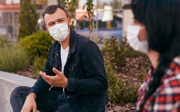 Young man in mask speaking with girlfriend