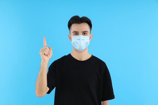 Young man in medical mask on blue background