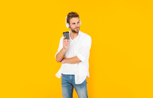 Young man in modern earphones with coffee cup online education back to school