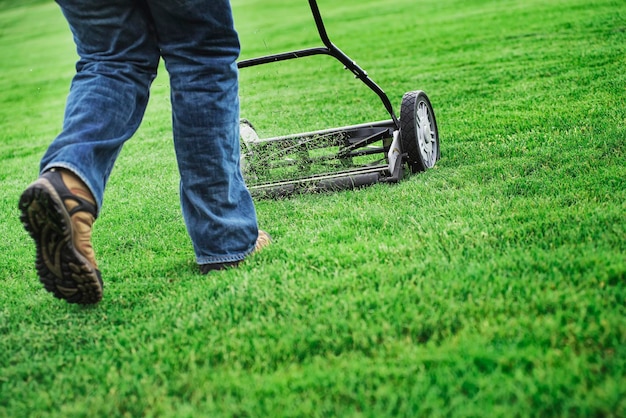 A young man mowing the grass on a property tending the garden using a petrol lawnmower