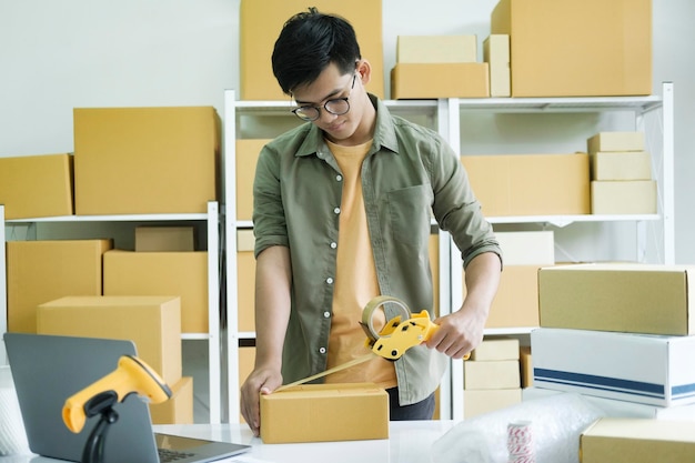 Young man packing product in box for online order xA