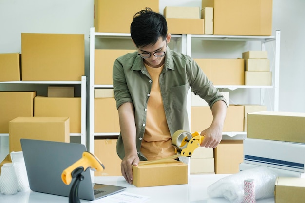 Young man packing product in box for online order xA