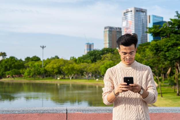 Young man in park during summer using phone