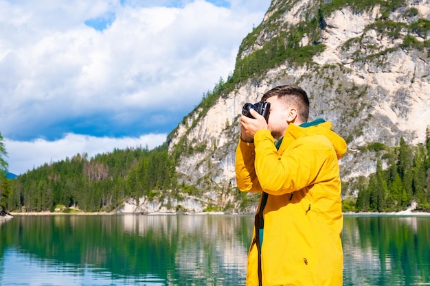 Young man photographer holding a camera and taking photos of the Alps