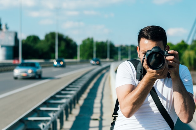 Young man photographer takes images with dslr camera outdoor