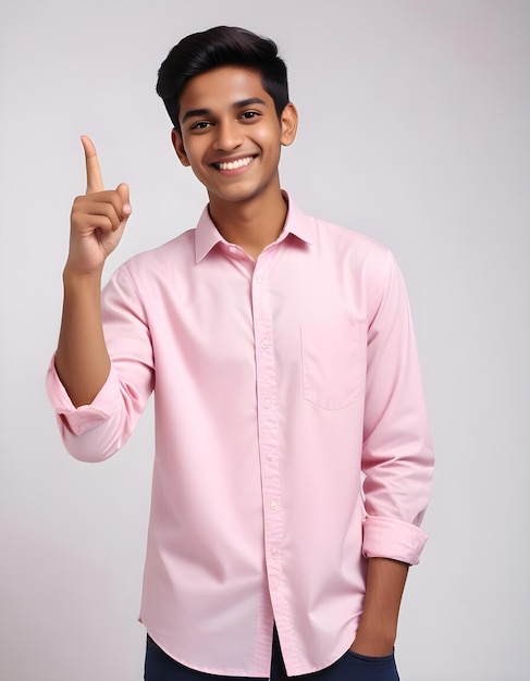 a young man in a pink shirt is smiling and pointing at the camera