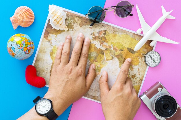 Young man planning travel on vacation trip with map. Top view.