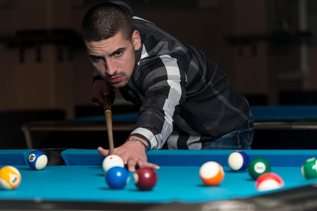 Young Man Playing Billiards Lined Up To Shoot Easy Winning Shot