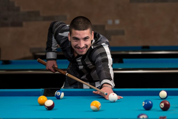 Young Man Playing Billiards Lined Up To Shoot Easy Winning Shot