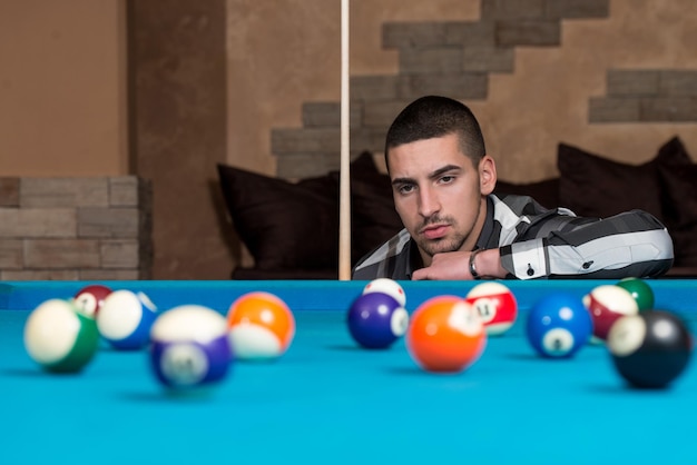 Young Man Playing Billiards Lined Up To Shoot Easy Winning Shot