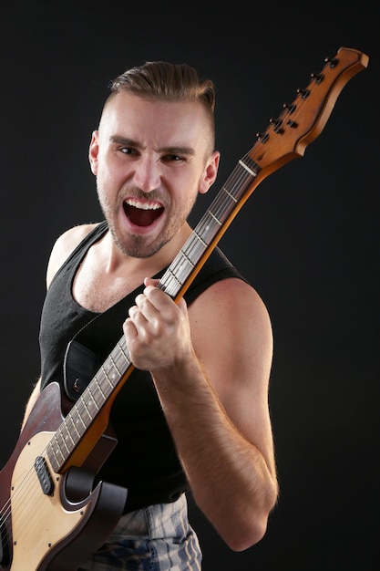 Young man playing on electric guitar close up