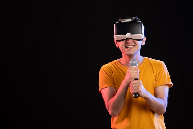 Young man playing virtual reality and singing on a black surface