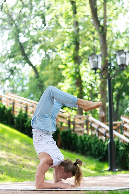 Young man practice yoga in the park. Yoga asanas in city park, sunny day. Concept of meditation, wellbeing and healthy lifestyle