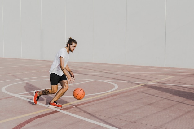 Young man practicing basketball in outdoors court