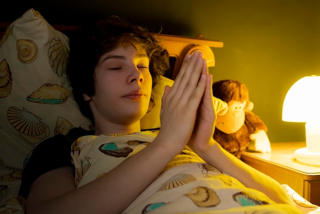 Young man pray in bed at night b