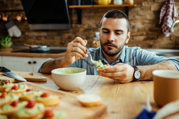 Young man preparing bruschetta in the kitchen