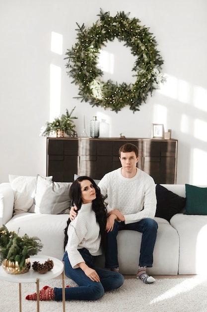 Young man and pretty woman posing in decorated for New year's party interior