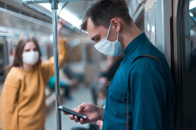 Young man in a protective mask looking at the screen of his smartphone. coronavirus in the city