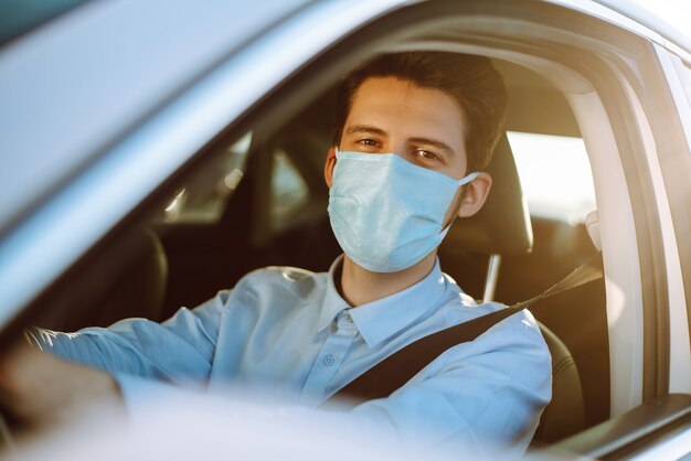 Young man in a protective mask sitting in the car